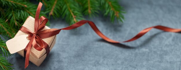 Confezione regalo di natale e nastro marrone con etichetta su sfondo grigio