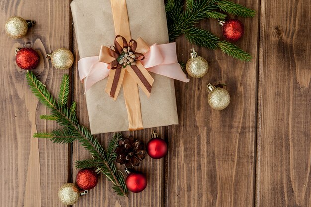 Подарочная коробка рождества, декор и ветвь ели на деревянном столе. Вид сверху с copyspace
