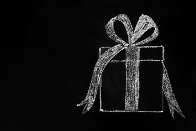 Christmas . Gift box drawn with white chalk on blackboard. copyspace.