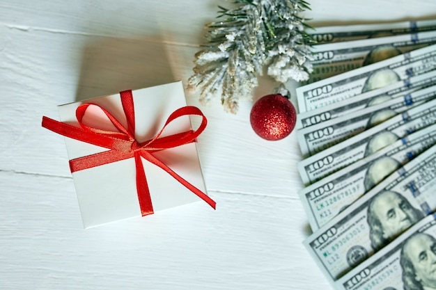 Christmas gift box en amerikaanse dollarbiljetten op witte houten achtergrond