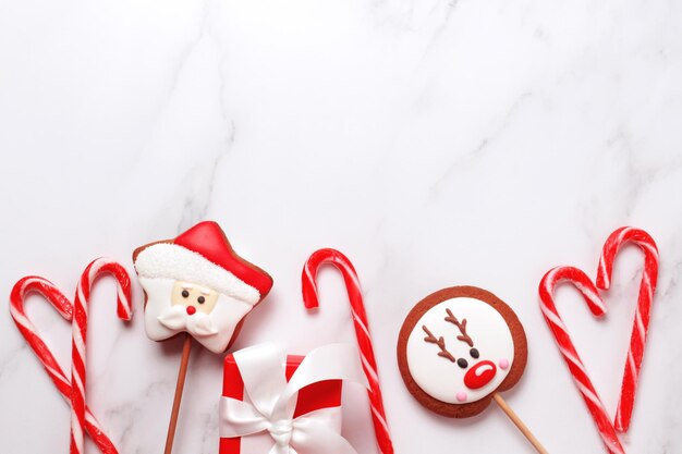 Christmas gift box gingerbread cookies and candy cane View from above over white marble background