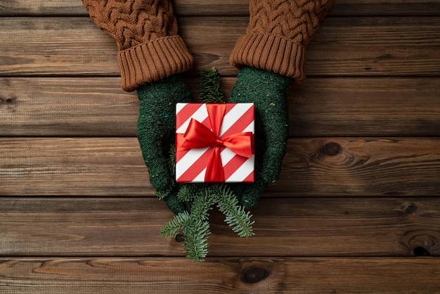 Christmas gift box in the hands of a woman on vintage wooden background