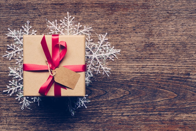 Christmas gift box placed and white snowflakes on wooden planks with space.