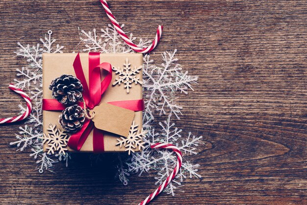 Christmas gift box placed and white snowflakes on wooden planks with space.