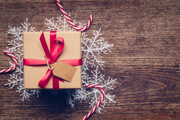 Christmas gift box placed and white snowflakes on wooden planks with space.