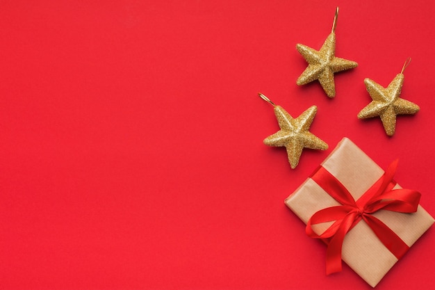 Confezione regalo di natale e tre stelle dorate su sfondo rosso