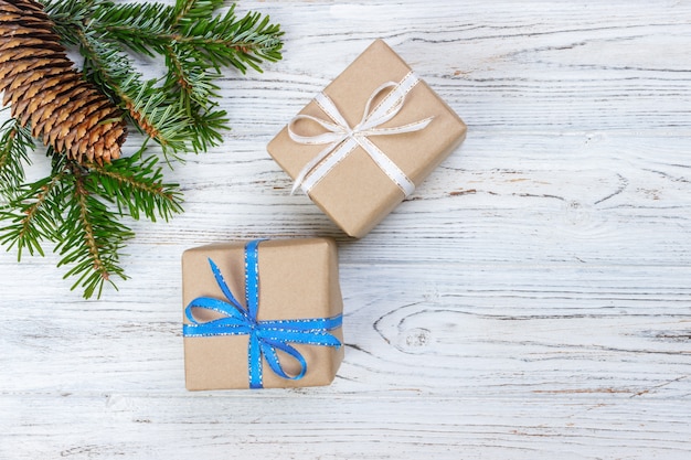 Christmas gift box on the white wooden table surface, spruce branch, pine cones, frame, top view,