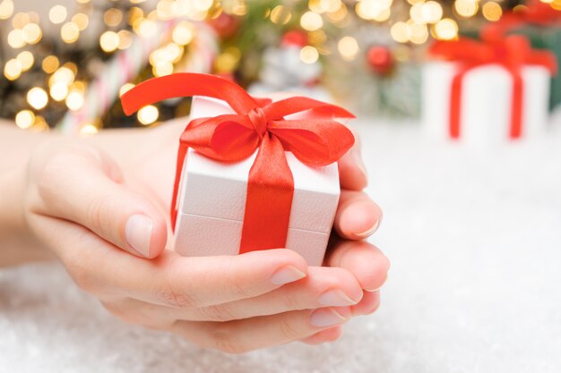 Christmas gift box with red ribbon and bow on the snow