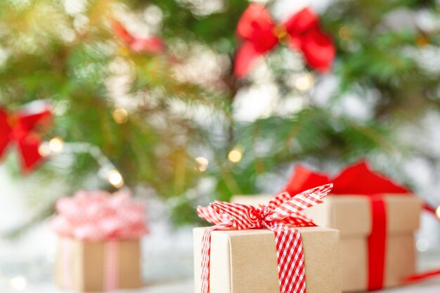 Christmas gift box with red ribbon under the christmas tree. Holiday greeting card. Happy New Year celebration.