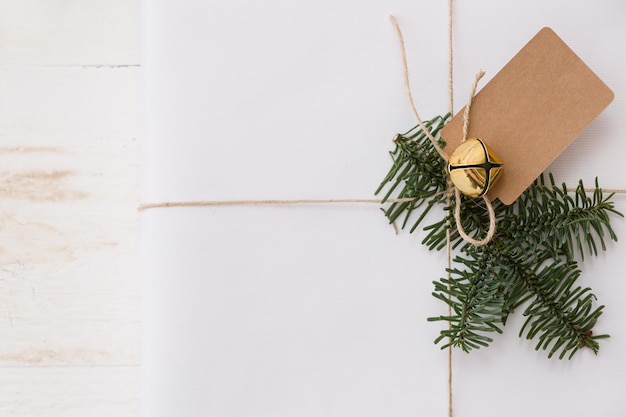 Christmas gift box with tag New Year present in white box with fir branches at white wooden table