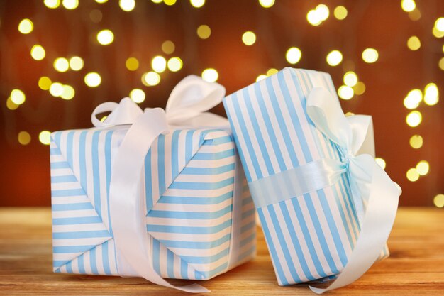 Christmas gift box on wooden table against brown bokeh background