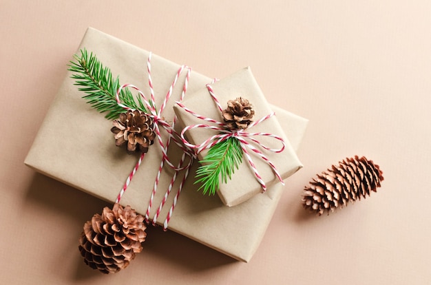 Christmas gift boxes decorated with fir tree twigs and cones on beige background