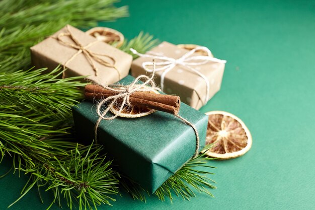 Рождественские подарочные коробки и ветки сосны с украшениями на зеленом фоне