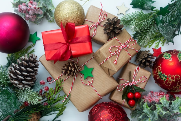 Рождественские подарочные коробки, стилизованные еловые ветки, сосновые шишки, белый фон.