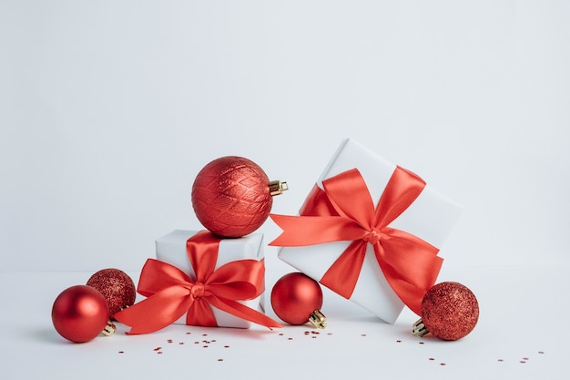 Рождественские подарочные коробки с красной лентой и украшениями, сложенными друг на друга на белом фоне