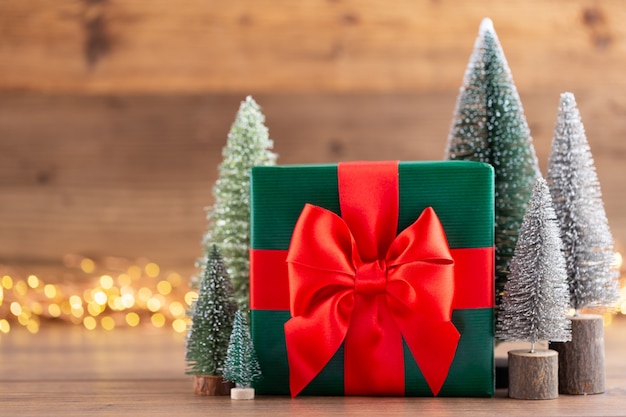 Christmas gift boxes with ribbons and tree on bokeh background.