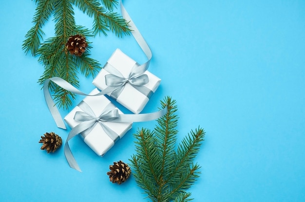 Christmas gift boxes with spruce branches and cones on blue