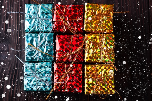 Christmas gift boxes on wooden table with snow.