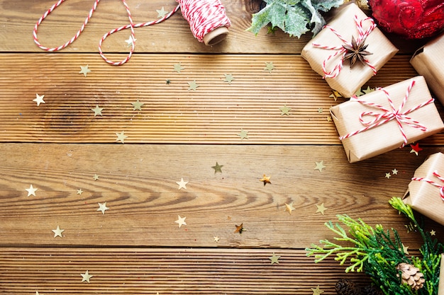 Christmas gift boxes wrapped in craft paper with fir branches, red baubles, pine cones.