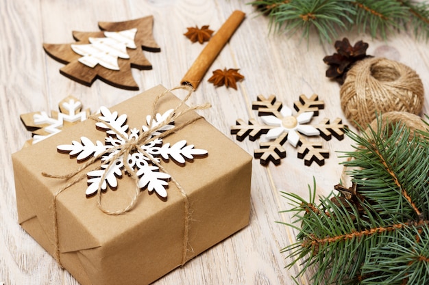 Рождественские подарочные коробки, завернутые в крафт-бумагу, еловые ветки, сосновые шишки, палочки корицы и звездчатого аниса
