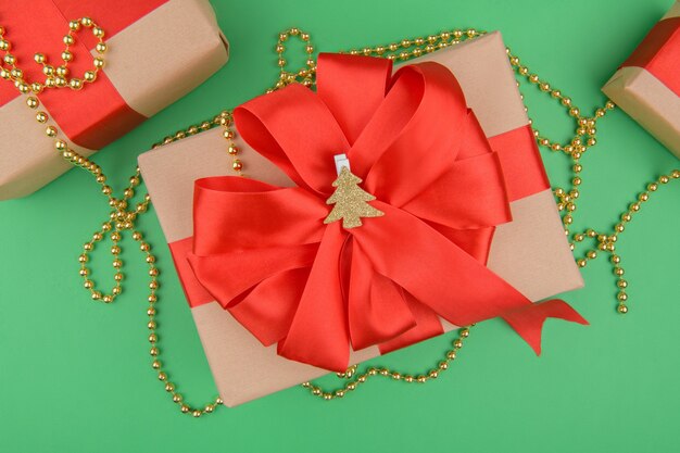 Christmas gift boxes wrapped in recycled kraft paper with red ribbon bow on a green background