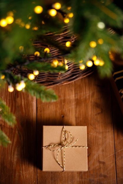 Christmas gift in a cardboard box on a brown wooden floor near a new year tree