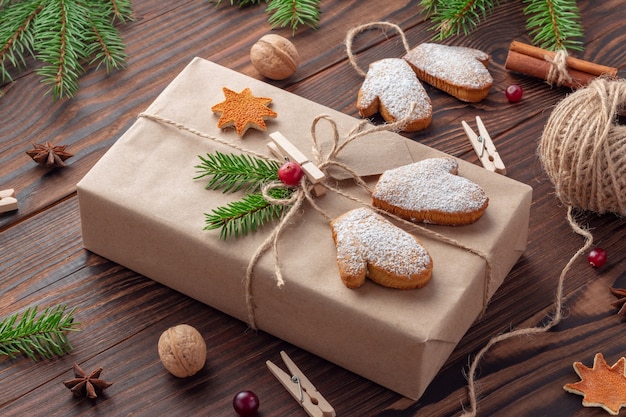 Christmas gift in eco-style tied by jute twine and decorated with mitten-shaped cookies