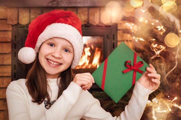 写真 クリスマスのプレゼント封筒 クリスマスの証明書 サンタの帽子の子供 クリスマスのライトの背景