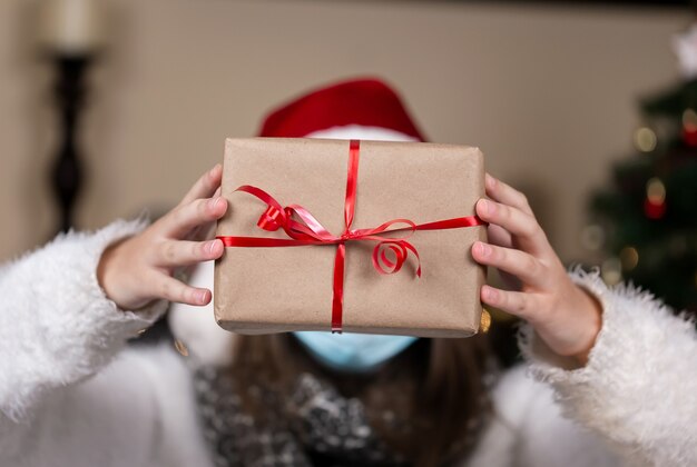 A Christmas gift. Faceless portrait woman holding gift box with red ribbon on a Christmas background. New year holidays concept