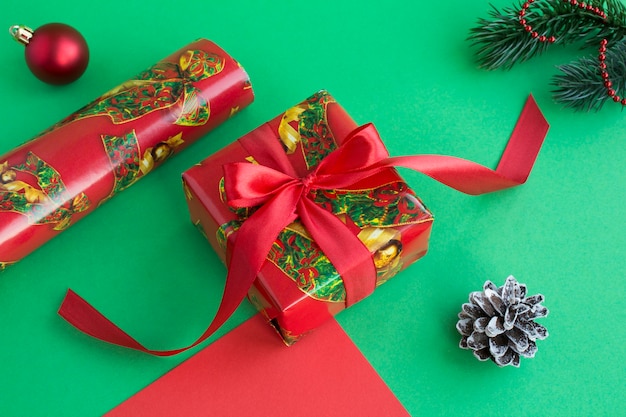 Рождественский подарок и подарочная упаковочная бумага на зеленом фоне