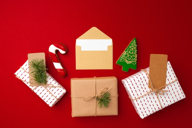 Christmas gift and gingerbread cookies on red background top view