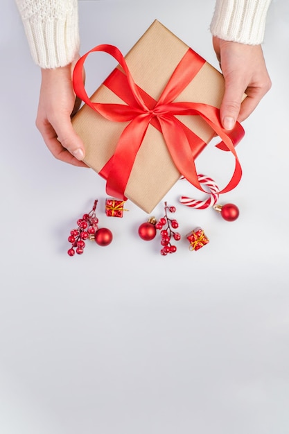 Christmas gift the girl is holding a craft gift with a red ribbon on a white background