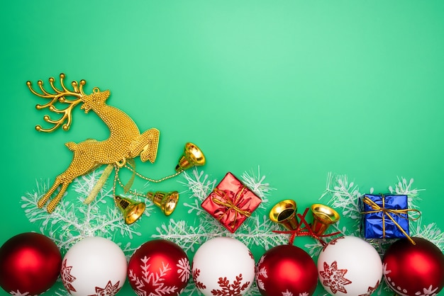 Christmas gift, gold reindeer and bell on green background. Flat lay, top view