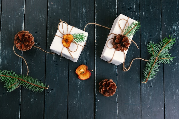 Christmas gift, knitted blanket, pine cones, fir branches on wooden table.