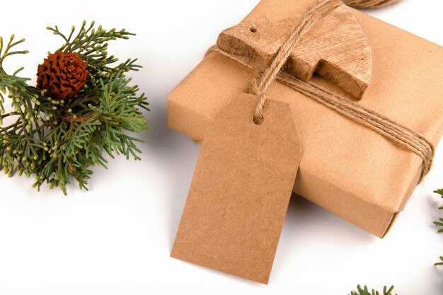 Christmas gift tag mock up with gift box wrapped in craft recycled paper with rope