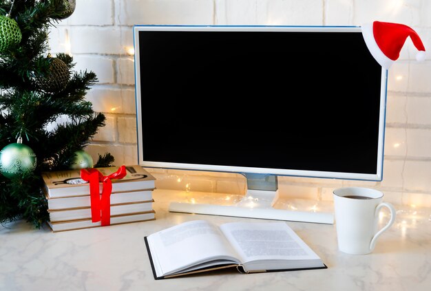 Christmas gift under the tree. desktop with computer, books and coffee.