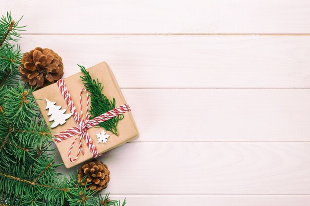 Christmas gift with fir branches and pine cones on wood white