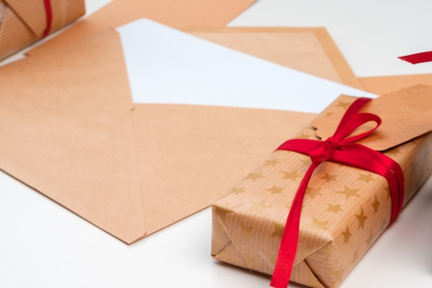 Christmas gift with red bow and greeting card on white wooden surface 