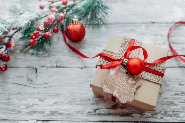 Christmas gift with a red ribbon on a wooden background with snowflakes