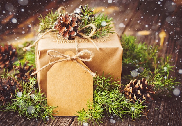 Christmas gift wrapped in kraft paper with decoration on a rustic wooden background from above.