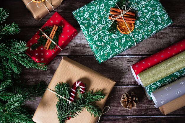 クリスマスプレゼント包装写真 クラフトレッドの装飾と上から紙のロールが付いた新年の箱 ろうそくロリポップ乾燥オレンジ