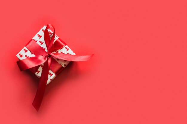 Christmas giftbox with red ribbon on red background