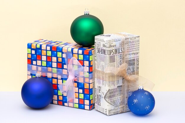 Christmas gifts in boxes and Christmas balls on a colored background