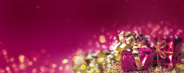 Christmas gifts in golden confetti and blur lights on pink  background