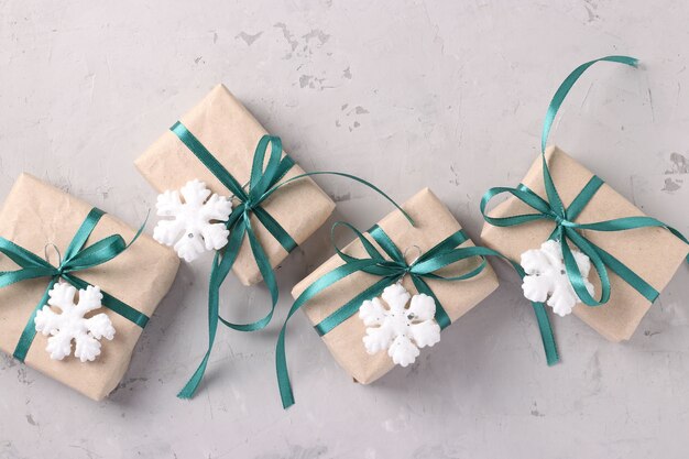 Christmas gifts in kraft paper with green ribbons on gray