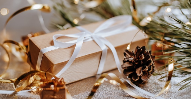 Рождественские подарки в огнях с шишками и еловыми ветками в праздничной новогодней атмосфере на серебряном фоне