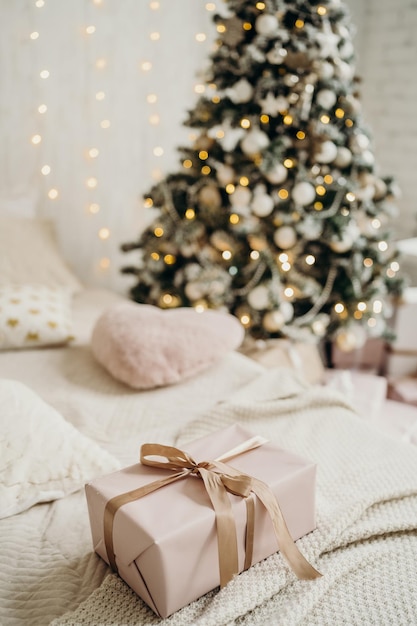 Christmas gifts in pink packaging with a bow on the background of the Christmas tree