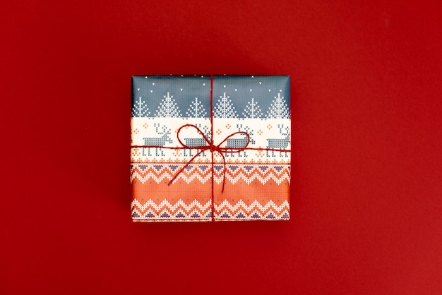 Photo christmas gifts presents on red background. simple, classic, red and white wrapped gift boxes with ribbon bows and festive holiday decorations.