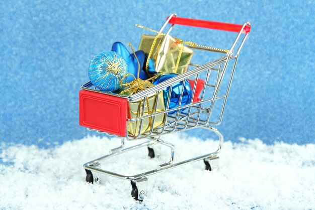 Christmas gifts in shopping trolley, on blue shiny background