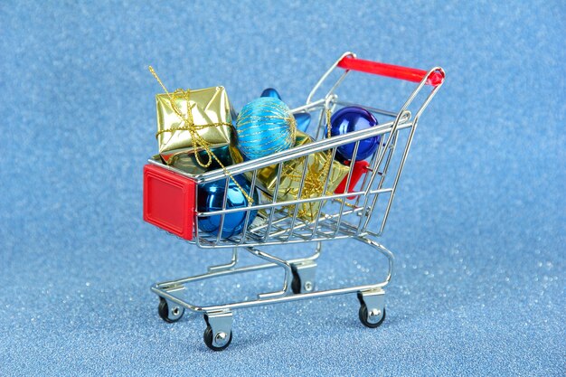 Christmas gifts in shopping trolley, on blue shiny background